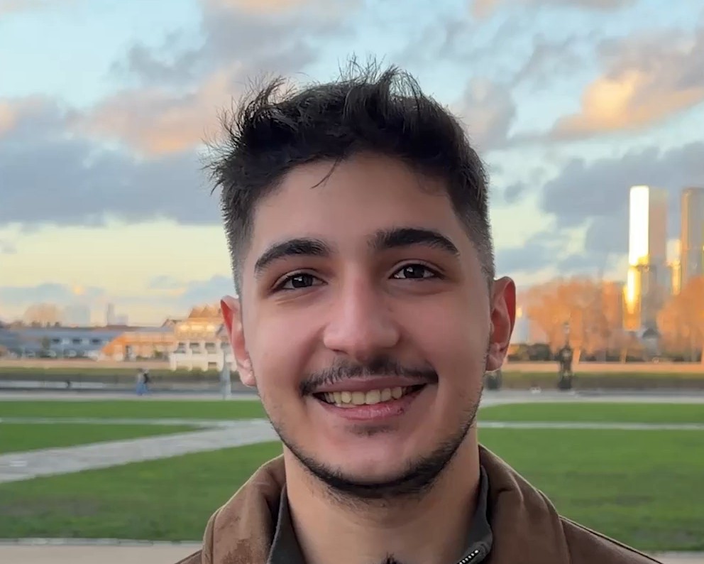 Aydın T., an IWS graduate who took A Levels in physics, maths and computer science, smiling at the camera in the light at the end of the day