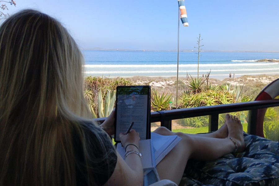 An IWS student doing her schoolwork on a tablet, on a deck that looks out to sea
