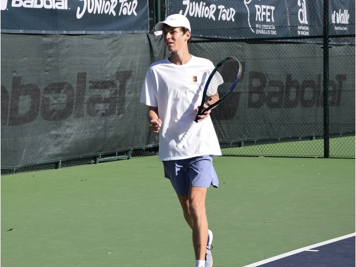Georgiy G., an IGCSE student, on a tennis court in a white cap with his racket