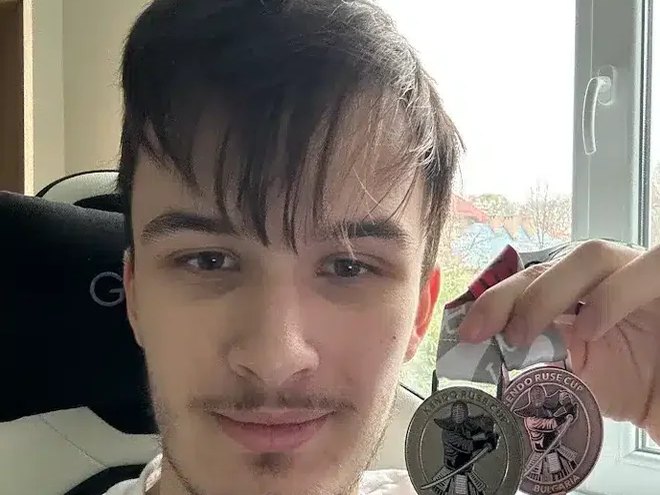 Maksim B., IWS Head Boy, holding two medals