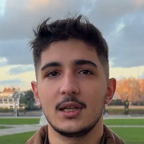 Aydın T. speaking to the camera in a park at sunset