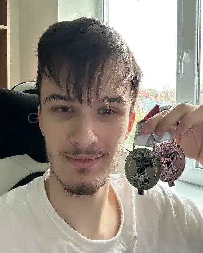 Maksim B. holding up two medals to the camera