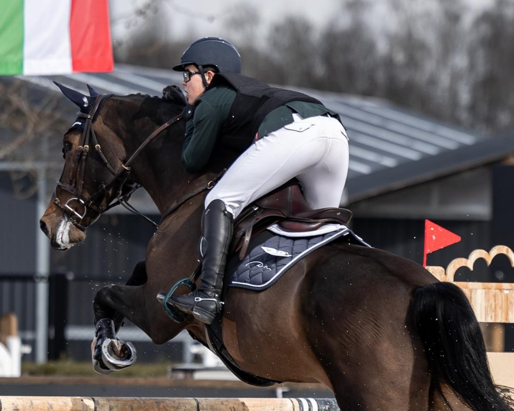 Peter G. and his horse in mid-jump over a fence, seen from the side