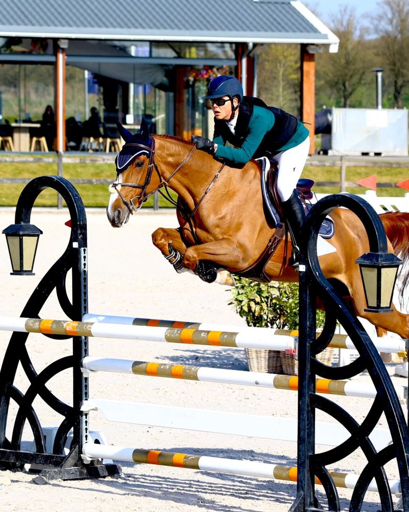 Peter G. and his chestnut horse clearing a black fence
