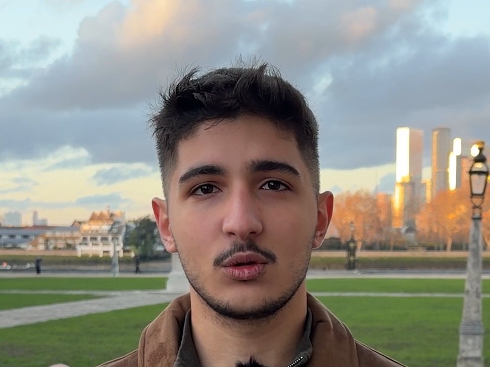 Aydın T., an IWS graduate, speaking to camera outdoors