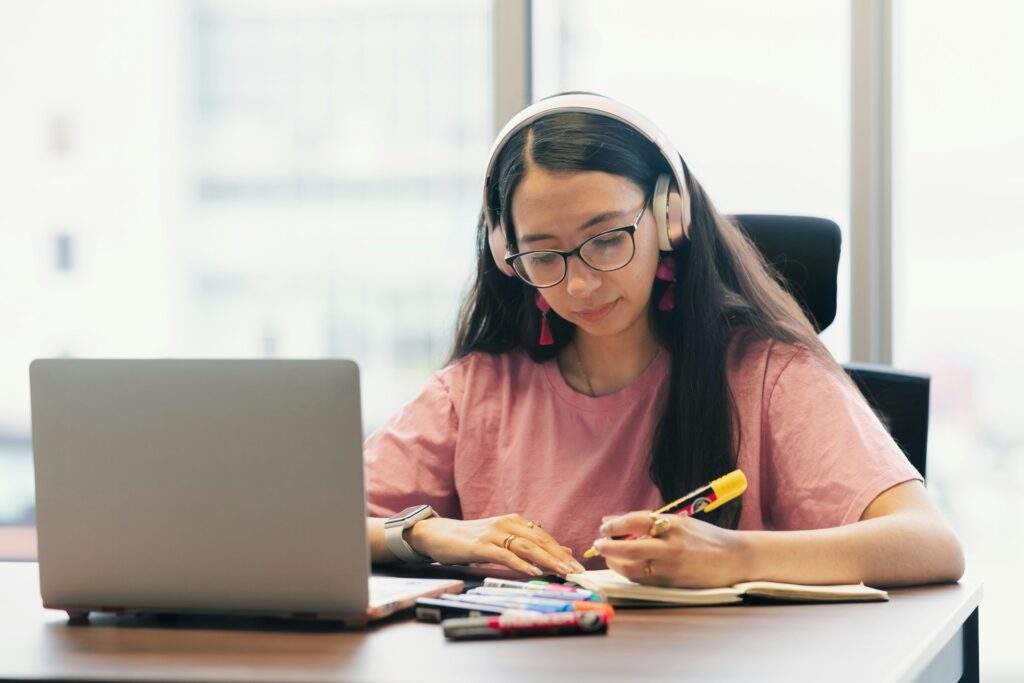 A student wearing headphones studying online on a laptop at home — IWS Online School