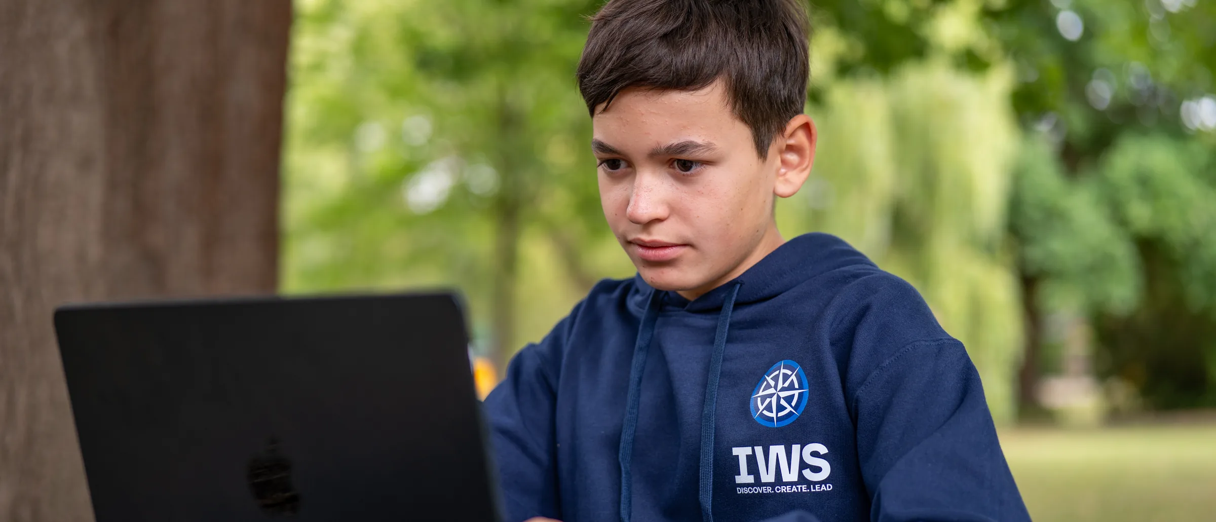An IWS student working outdoors on a laptop