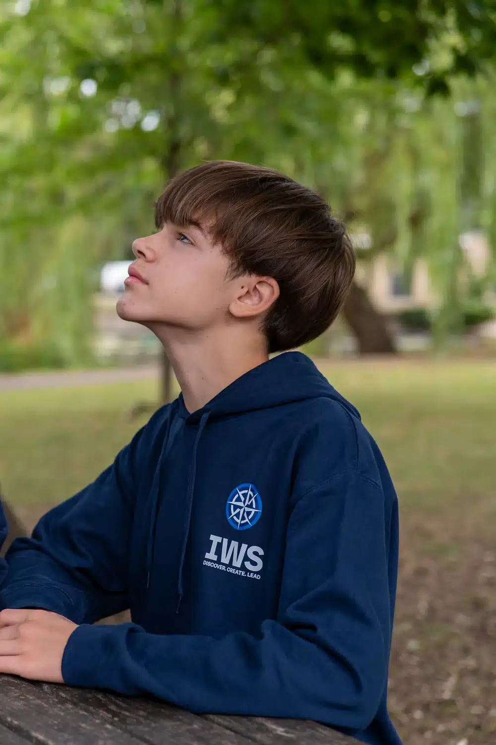 IWS Online School student in school hoodie, outdoors between lessons
