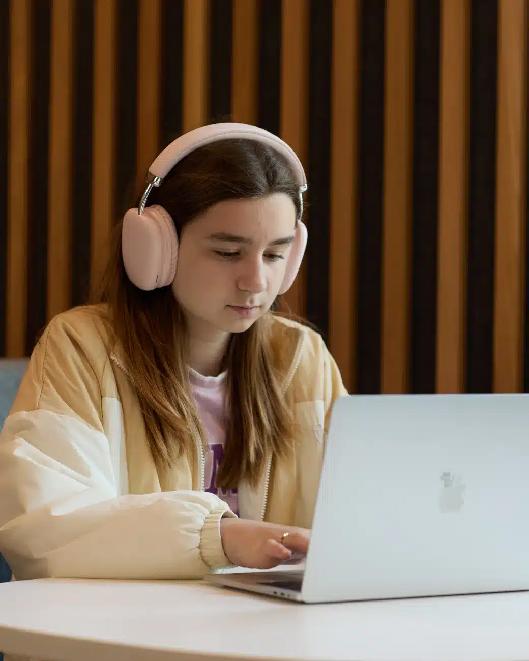 An IWS student wearing a headset, following a live lesson on her laptop